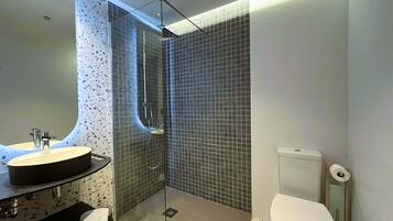 A modern bathroom with a glass-enclosed shower, a round sink, and a toilet.