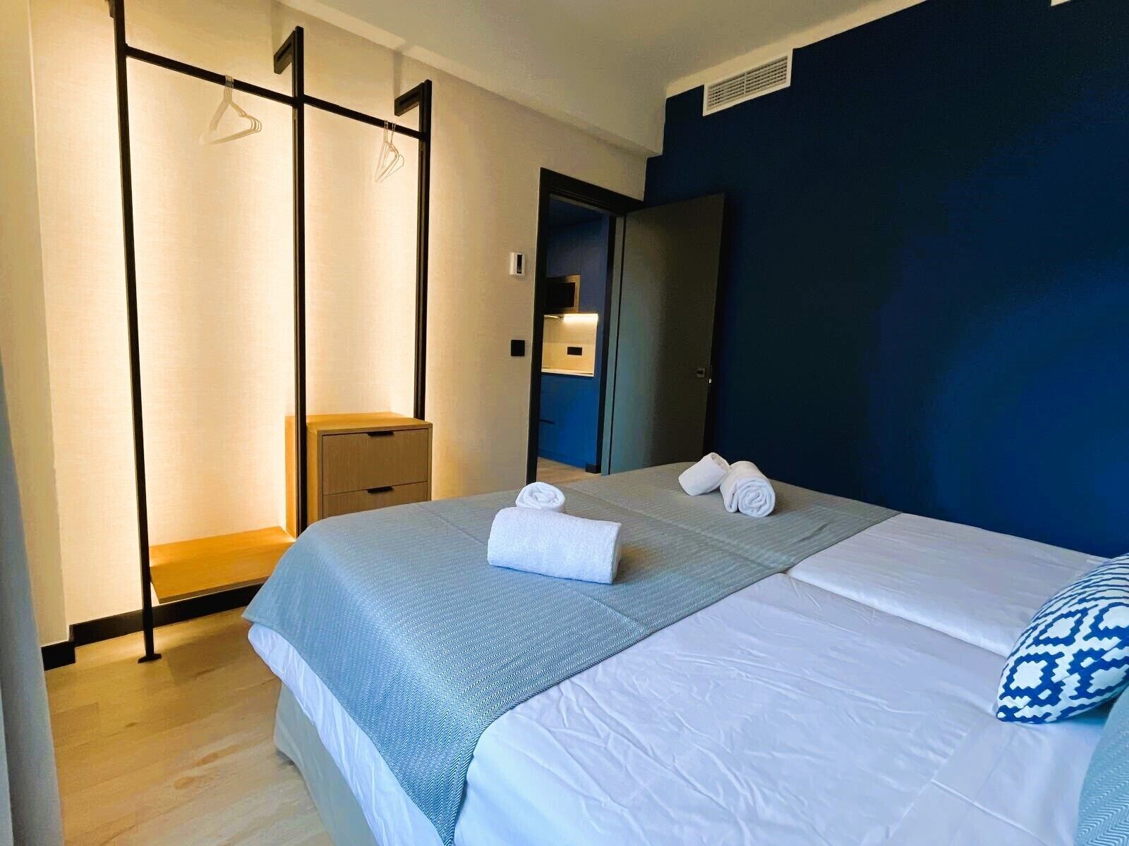 Una habitación de hotel moderna con una cama grande, un armario y un baño visible a través de una puerta abierta.
