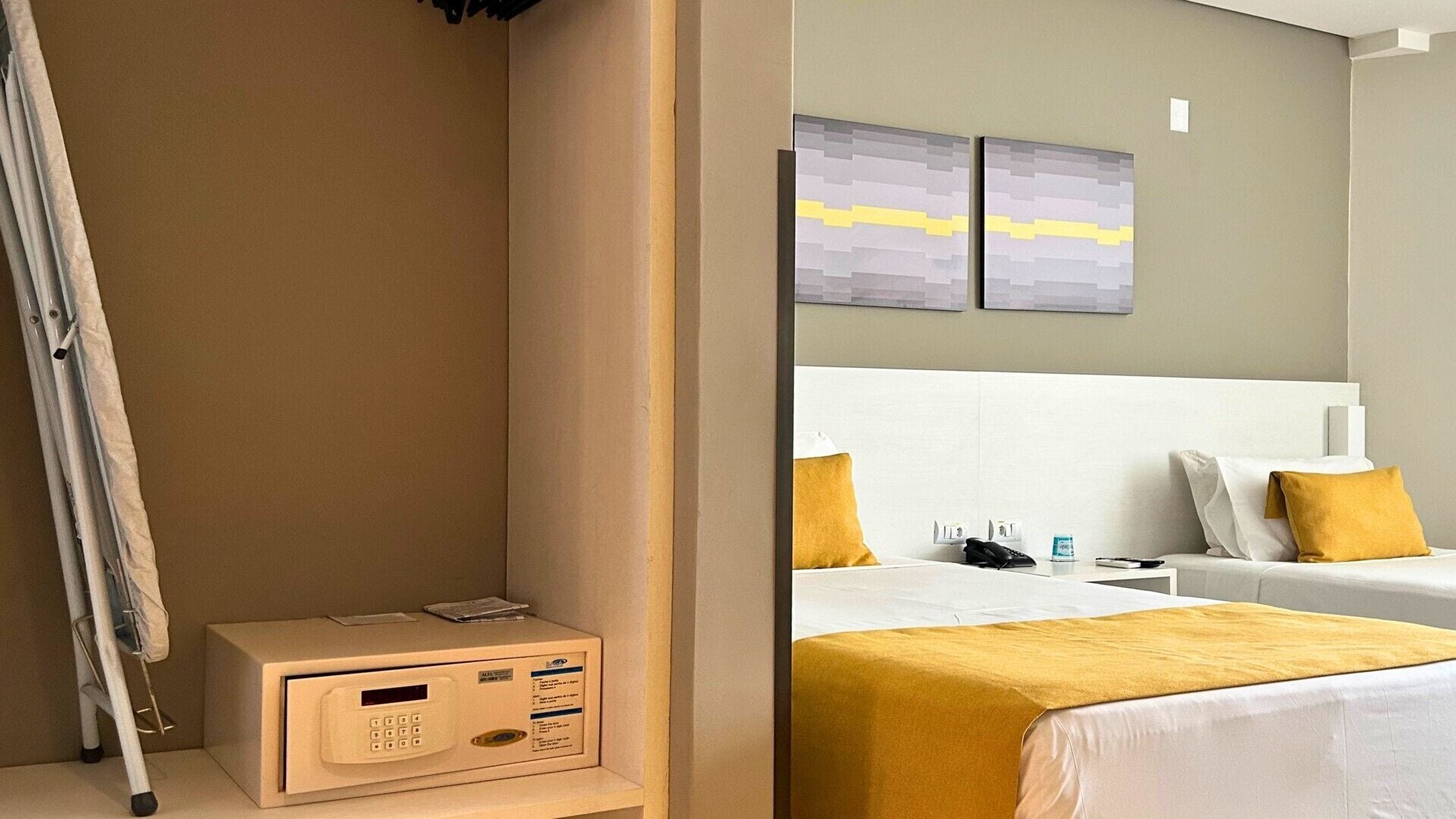 A hotel room with a bed, bedside table, and a control panel.