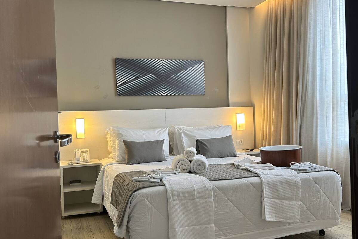 A hotel room with a bed, bedside tables, a telephone, and a wall-mounted artwork.