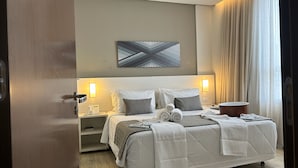 Une chambre d’hôtel équipée d’un lit, de tables de chevet, d’un téléphone et d’une œuvre d’art accrochée au mur.
