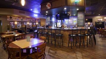 A restaurant interior with wooden tables and chairs, a bar area, and various menu boards.