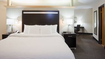 A hotel room with a large bed, bedside tables with lamps, a desk, and a chair.