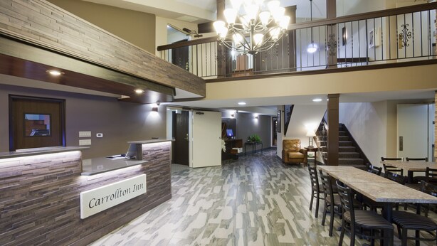 A reception area with a sign reading "Carrollton Inn," a staircase, and a dining area with tables and chairs.