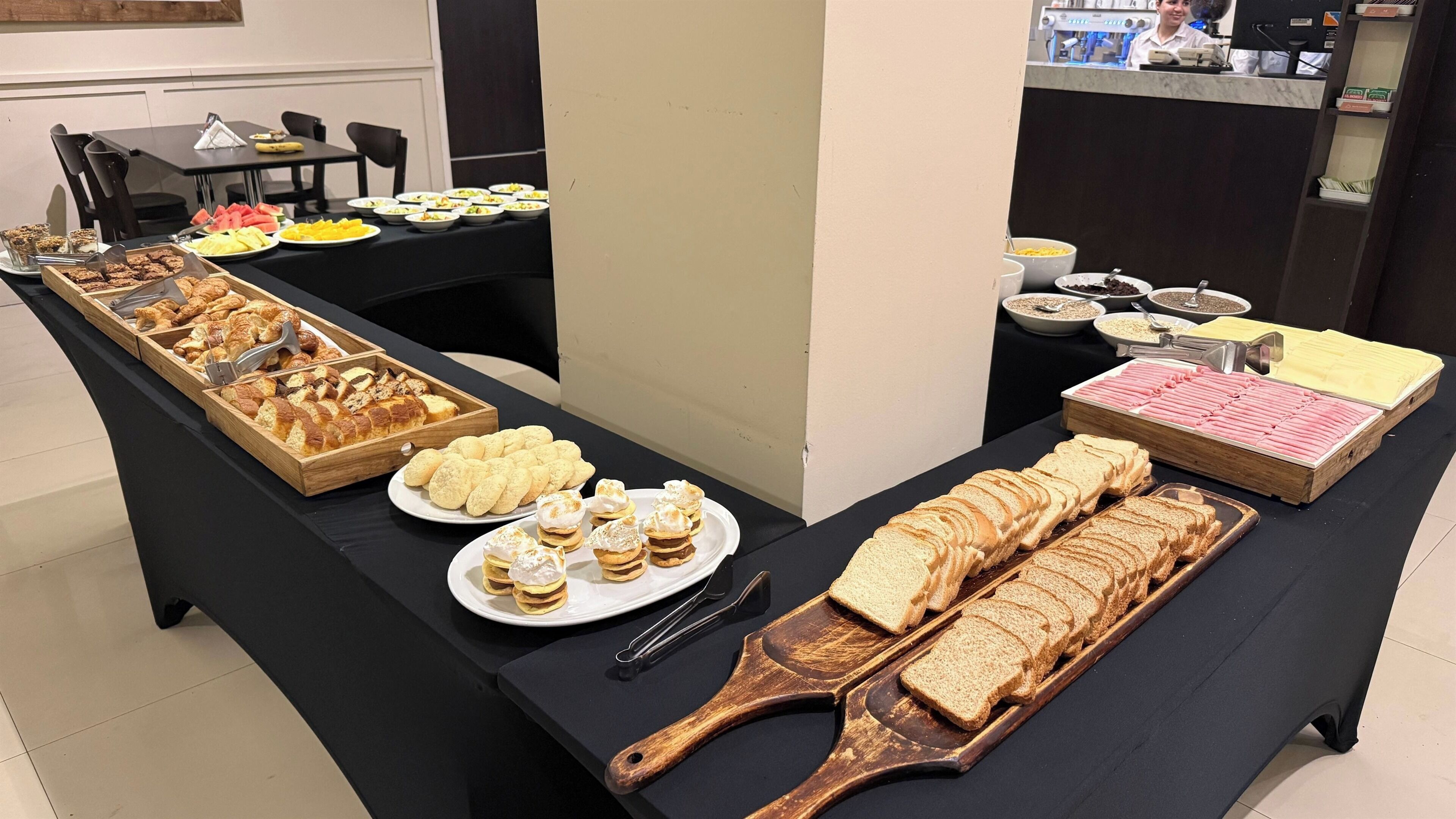 A buffet table with various food items including pastries, bread, and desserts.