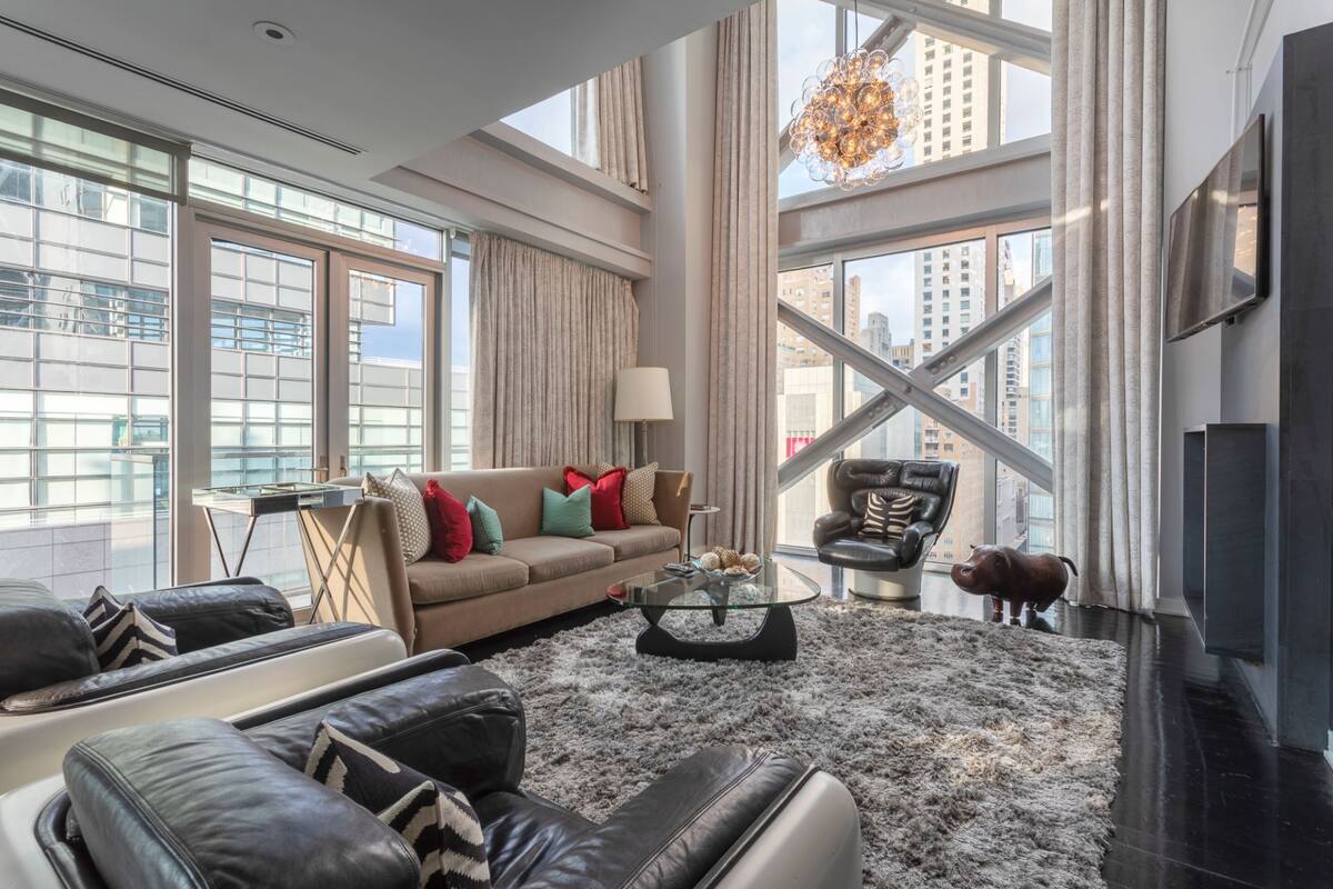A modern living room with a sofa, coffee table, and a large window with a city view.