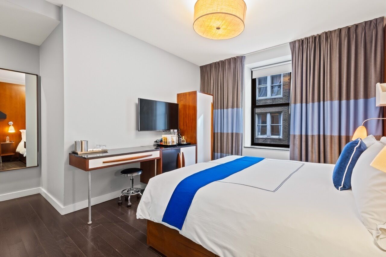 Une chambre d’hôtel équipée d’un lit, d’un bureau, d’une chaise et d’un téléviseur.