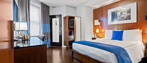 A hotel room with a bed, bedside table, lamp, and a large window with curtains.