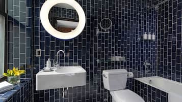 A modern bathroom with dark blue tiles, a white sink, a toilet, and a bathtub.
