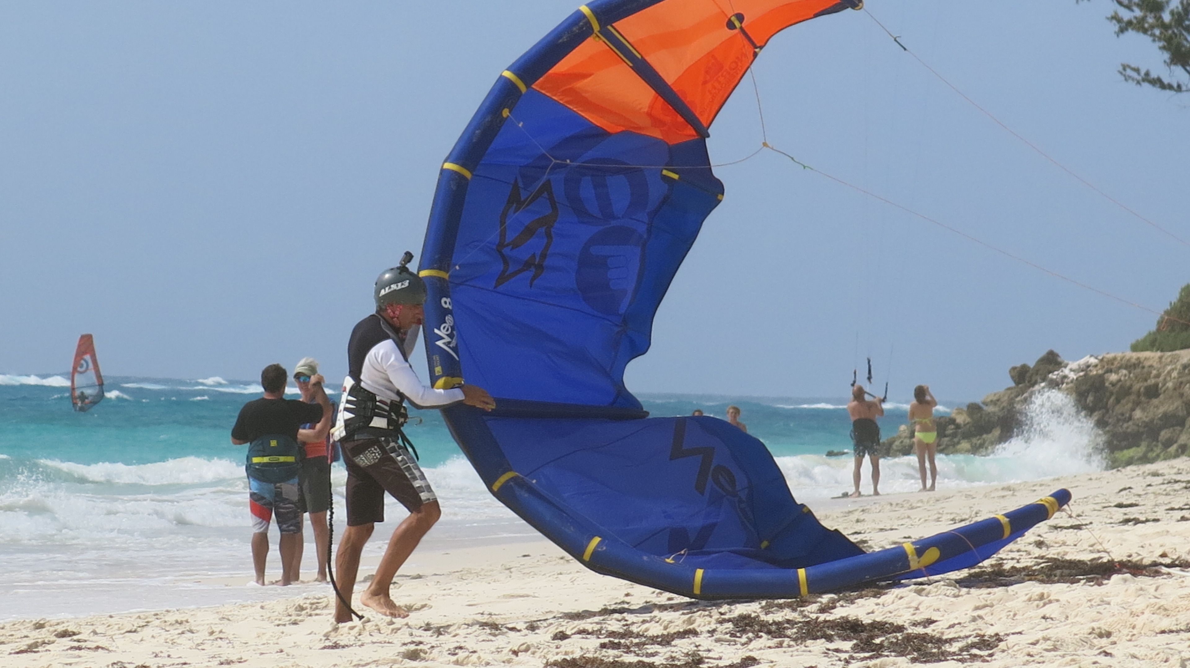 Una spiaggia con persone che praticano windsurf e kitesurf.