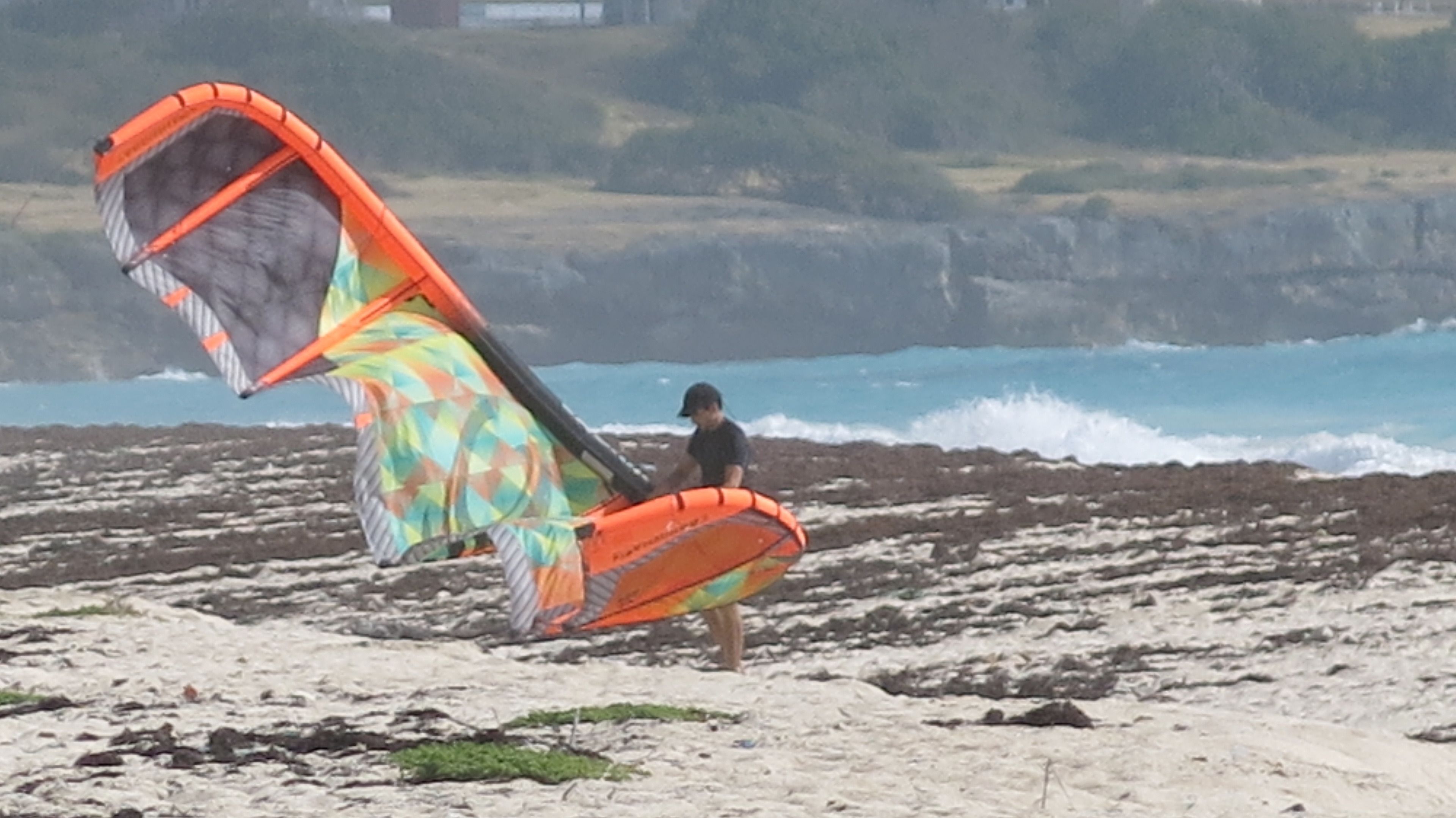 Una playa con una persona sosteniendo una cometa colorida.