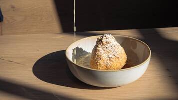 A hand sprinkling powdered sugar over a dessert in a bowl.
