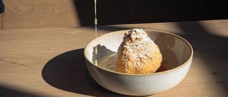 A hand sprinkling powdered sugar over a dessert in a bowl.