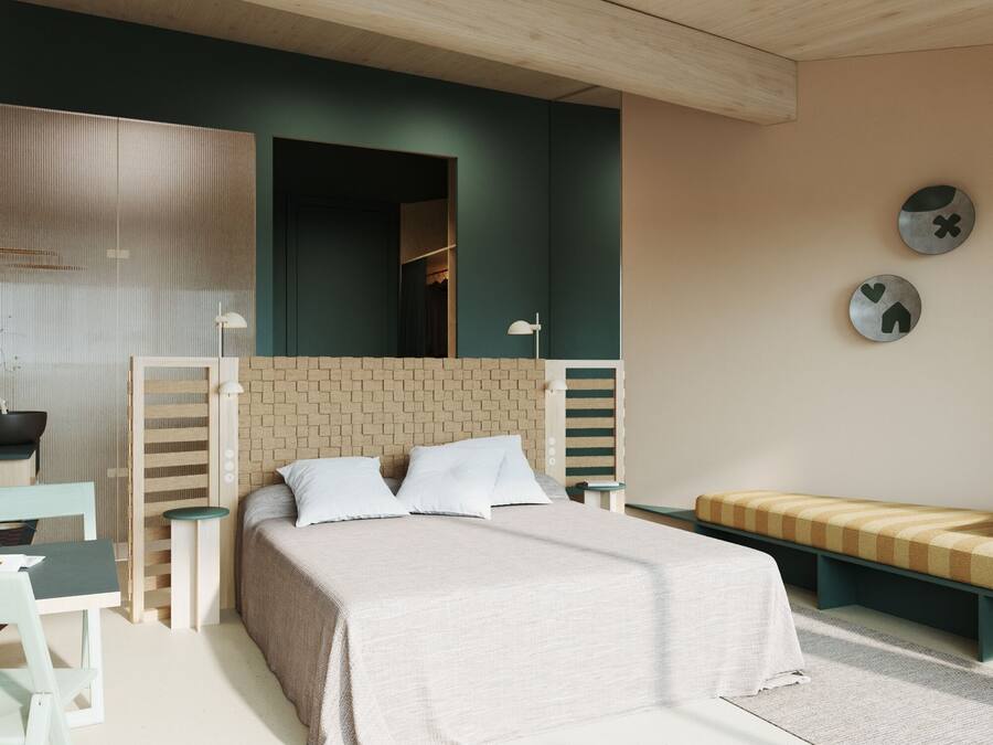 Un dormitorio con cama, mesitas de noche, un banco y un espejo en la pared.