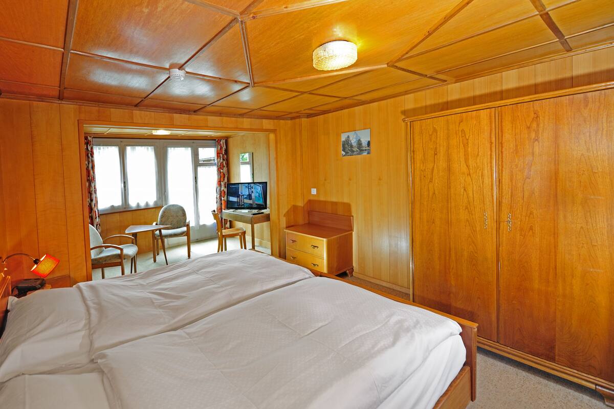 Ein Zimmer mit einem großen Bett, einem Schreibtisch mit Computer und einem Kleiderschrank.