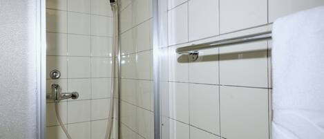 Une douche fermée par des parois en verre, dotée d’un pommeau de douche à main et d’un flexible à main.