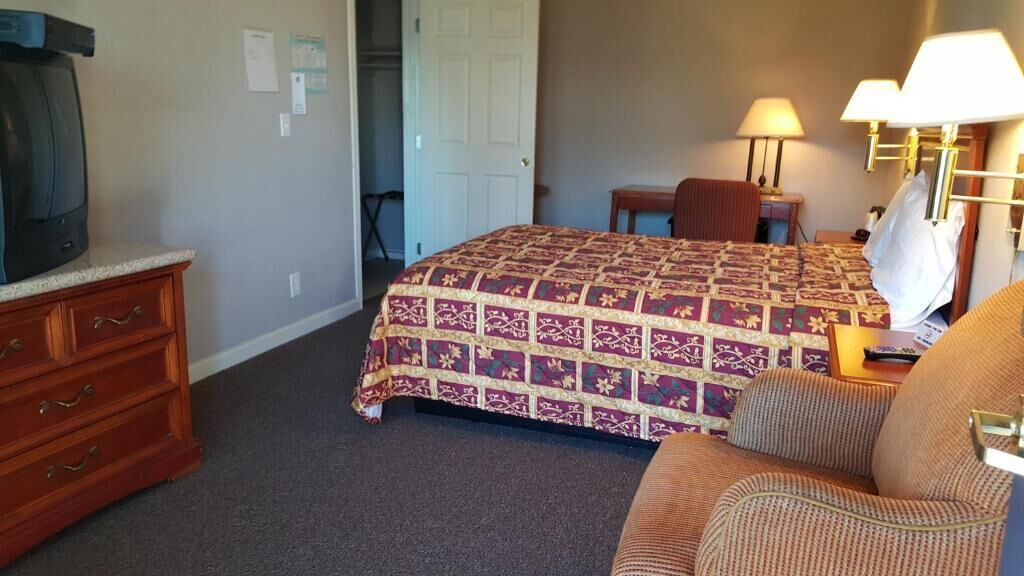 A hotel room with a bed, a television, a desk, and a chair.
