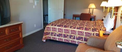 A hotel room with a bed, a television, a desk, and a chair.