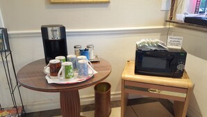 A small table with a coffee maker, mugs, and a microwave on a wooden stand. - Pacific Motel (Gridley)