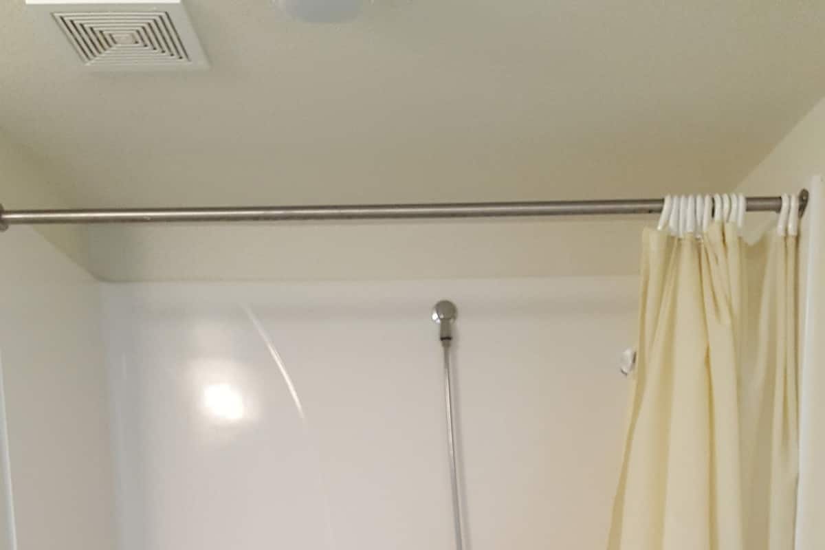 A shower with a grab bar, a showerhead, and a curtain.