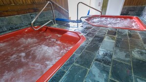 Two hot tubs with metal railings and a tiled floor.