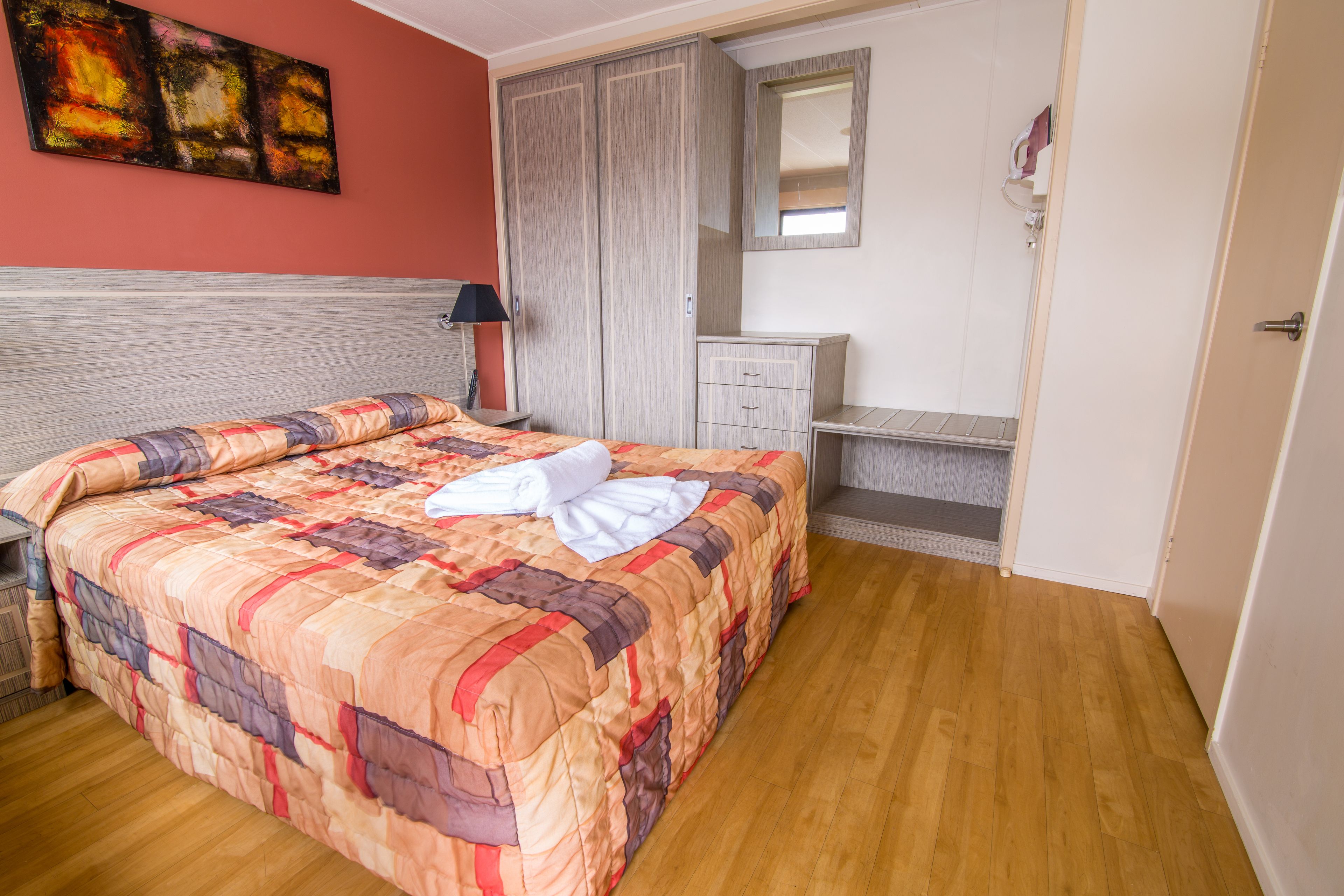 Un dormitorio con cama, armario, cómoda y espejo.