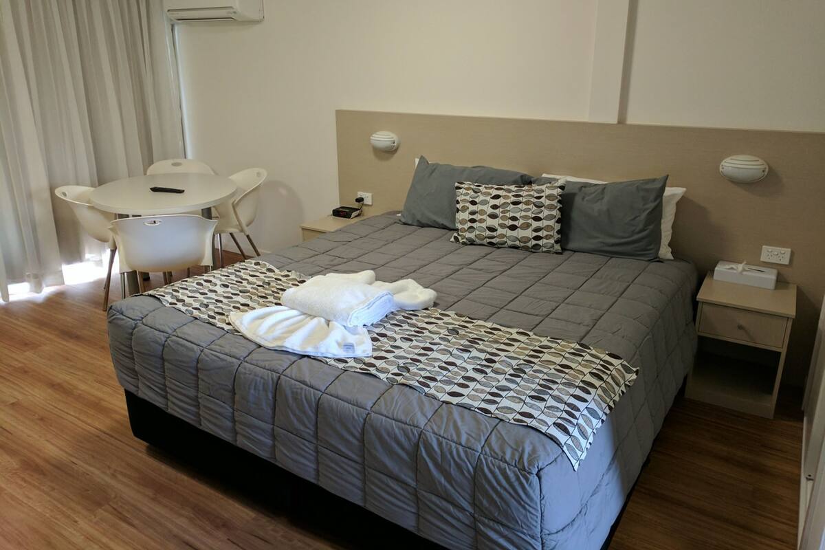 A hotel room with a bed, bedside tables, a desk, and a chair.