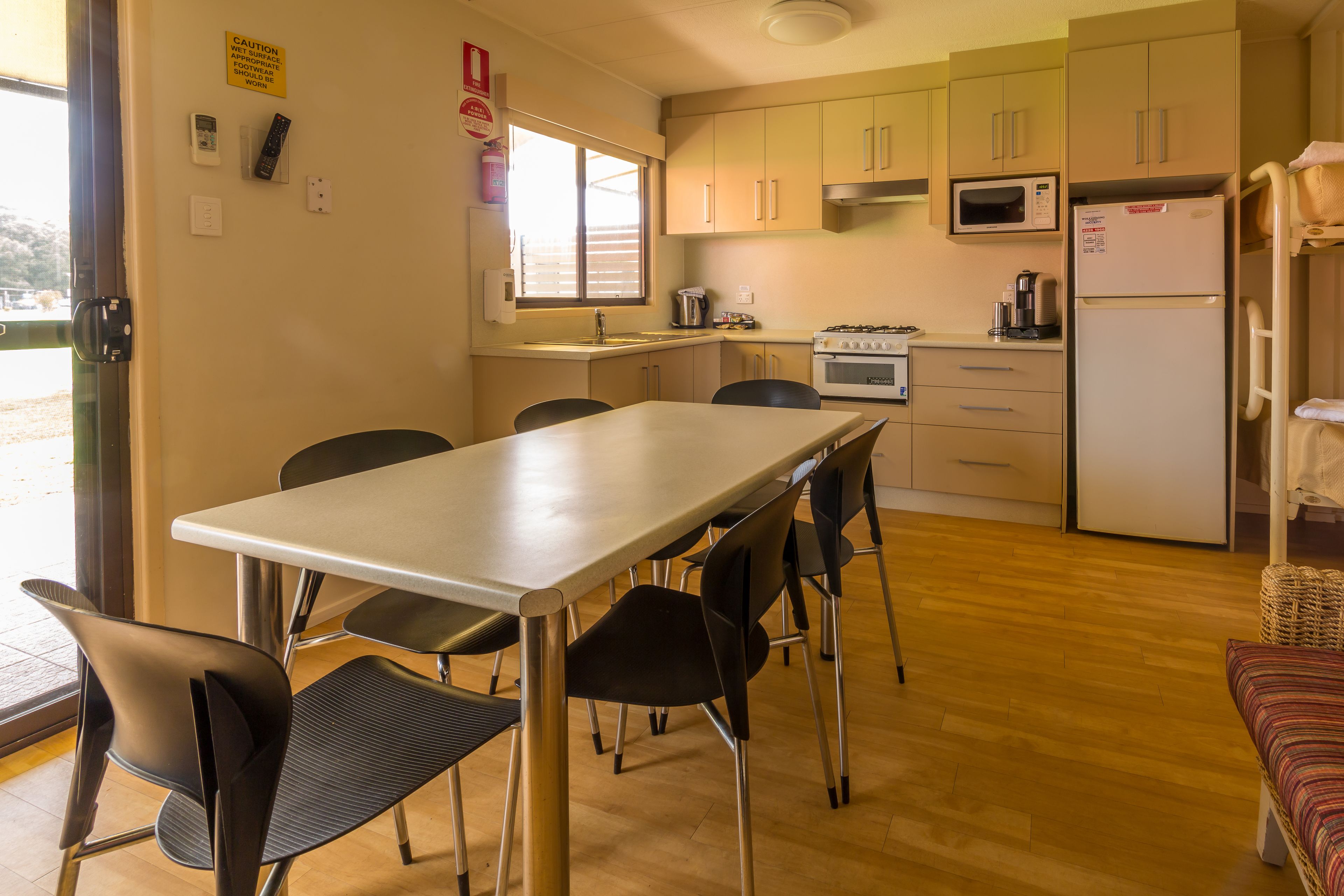 A compact kitchen with a dining area, including a table and chairs, a microwave, a refrigerator, and a stove.