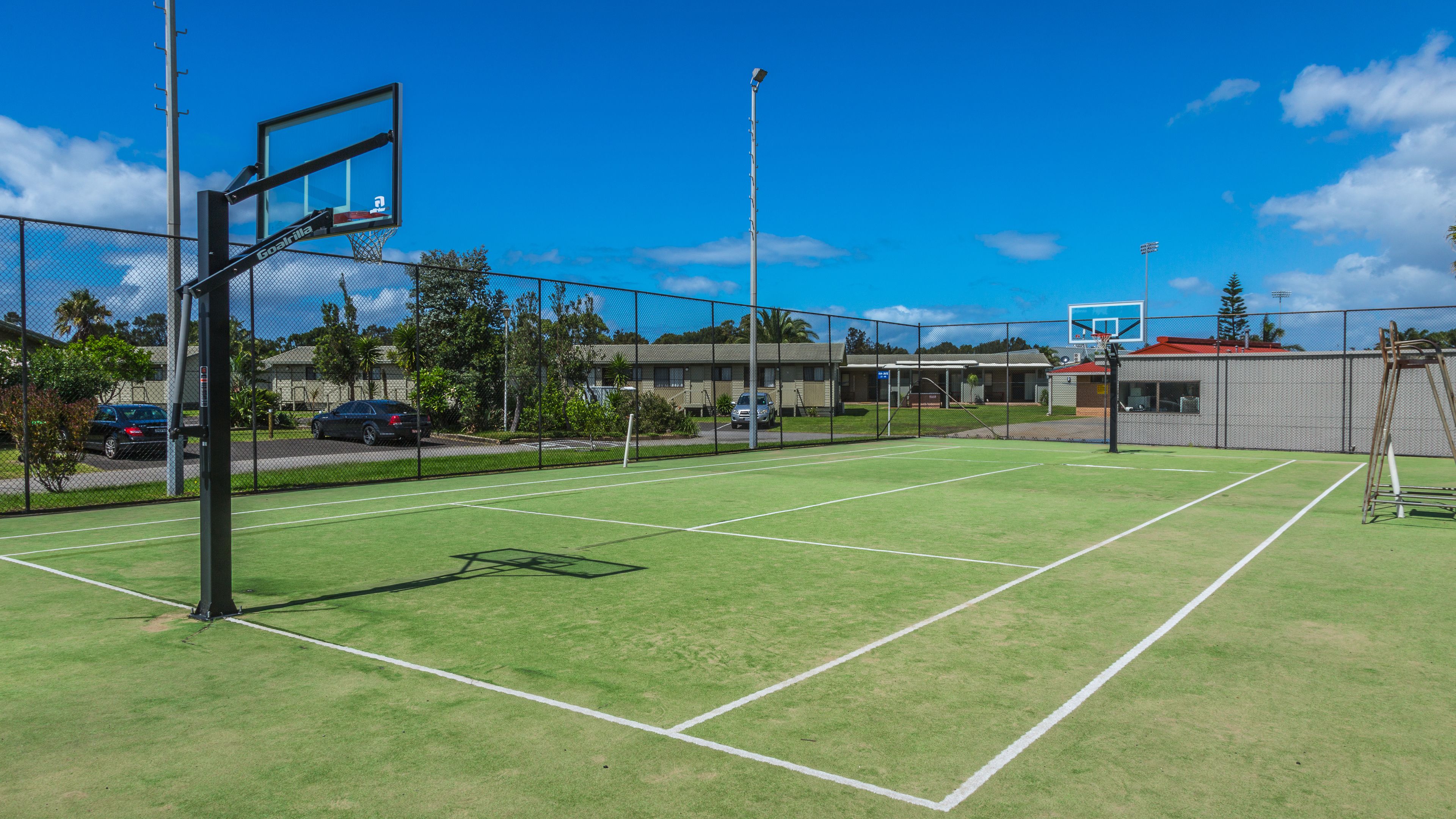Ein Basketballplatz im Freien mit Zaun, Korb und Netz.