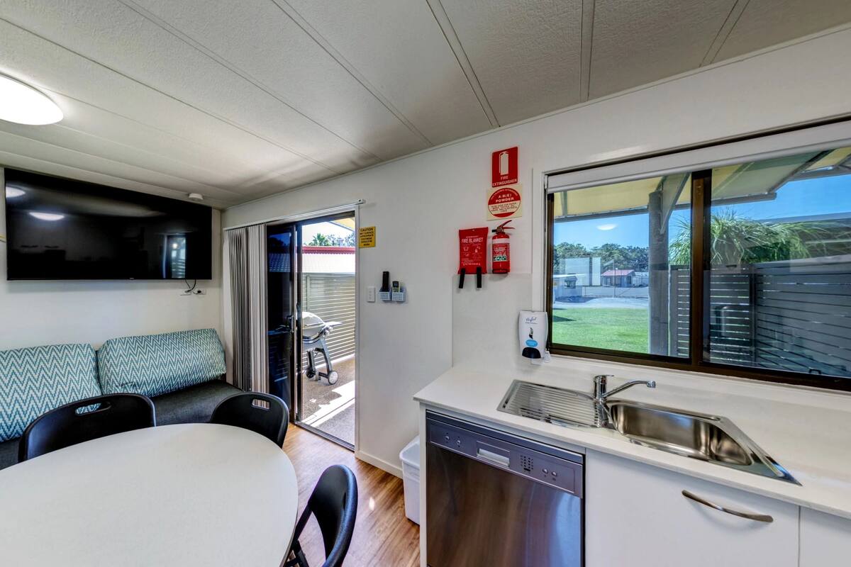 A compact kitchen with a dishwasher, a sink, and a window offering a view of the outdoors.