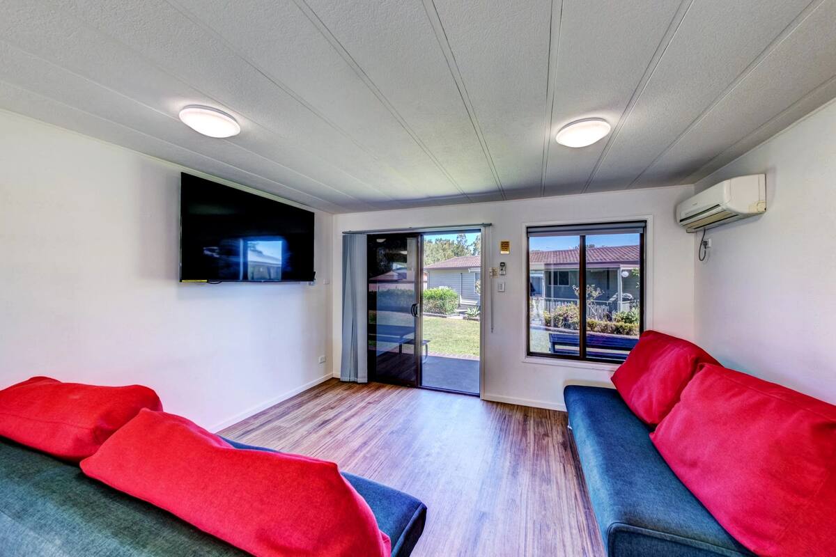 A room with two sofas, a flat-screen TV, and a sliding glass door leading to an outdoor area.