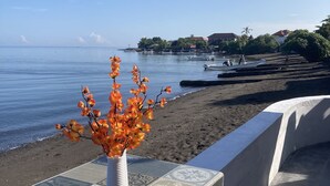 Vista de la playa con un banco de baldosas y un florero con flores naranjas.