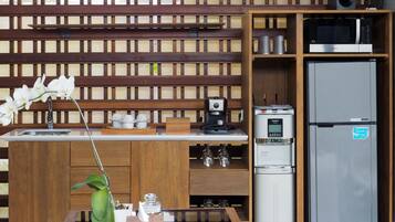 A modern kitchen with a wooden island, a built-in microwave, a refrigerator, and a coffee machine.