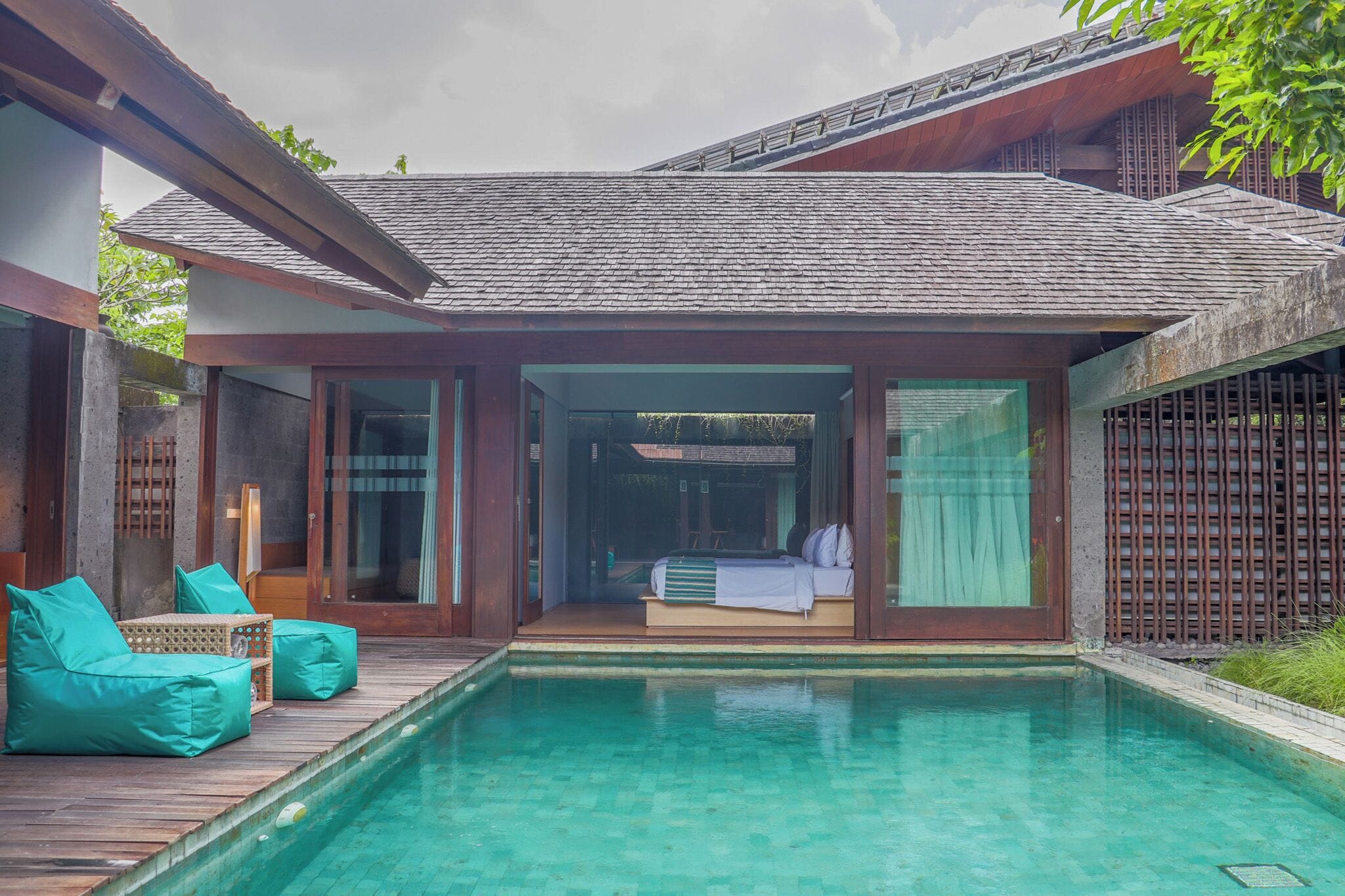 Uma villa moderna com piscina, deck de madeira e cama com vista.
