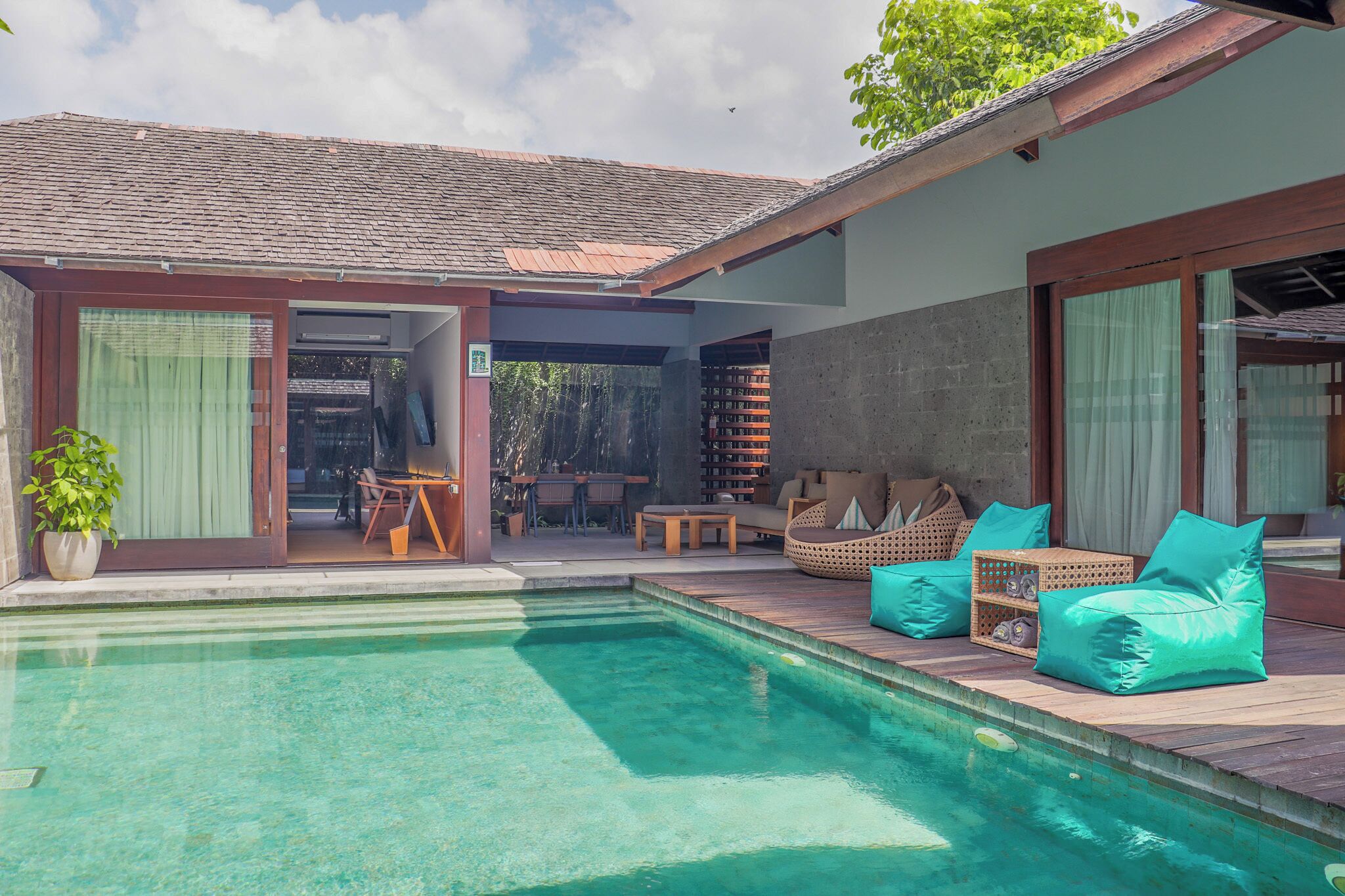 A poolside area with a wooden deck, seating, and a covered patio.