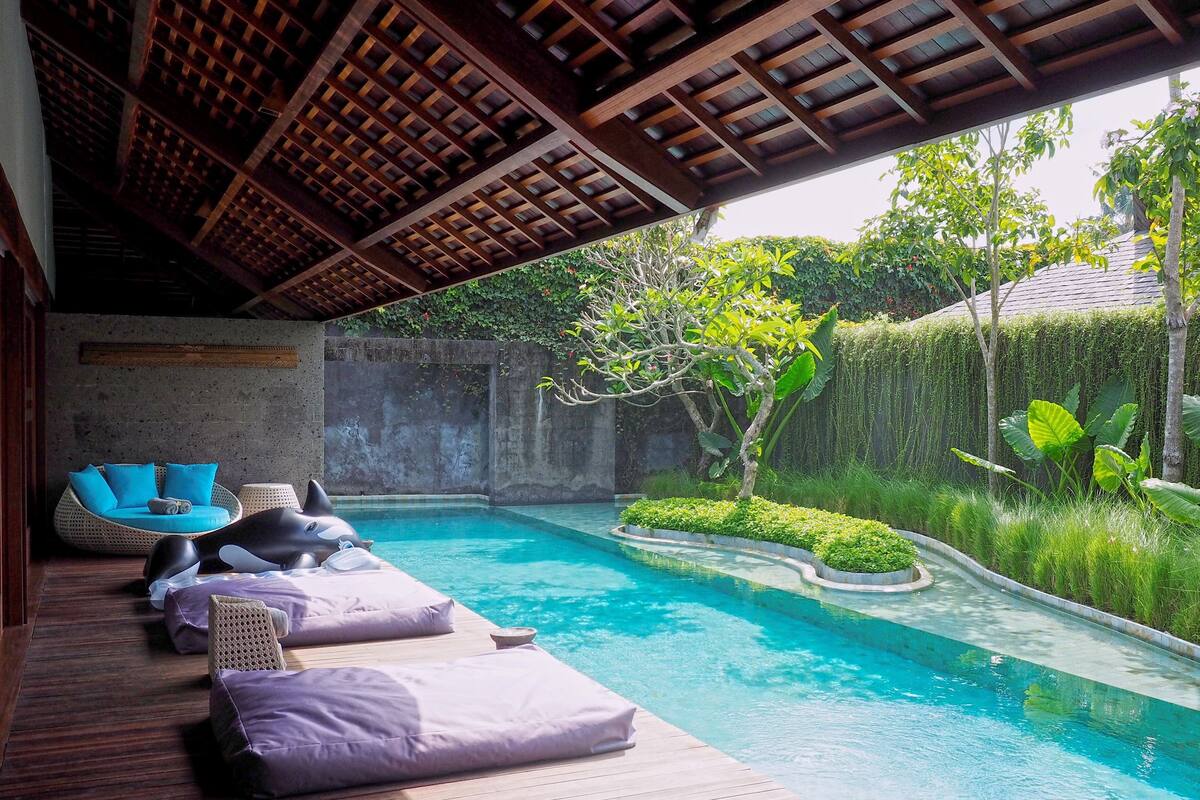 A pool area with wooden deck, lounge chairs, and a small garden.