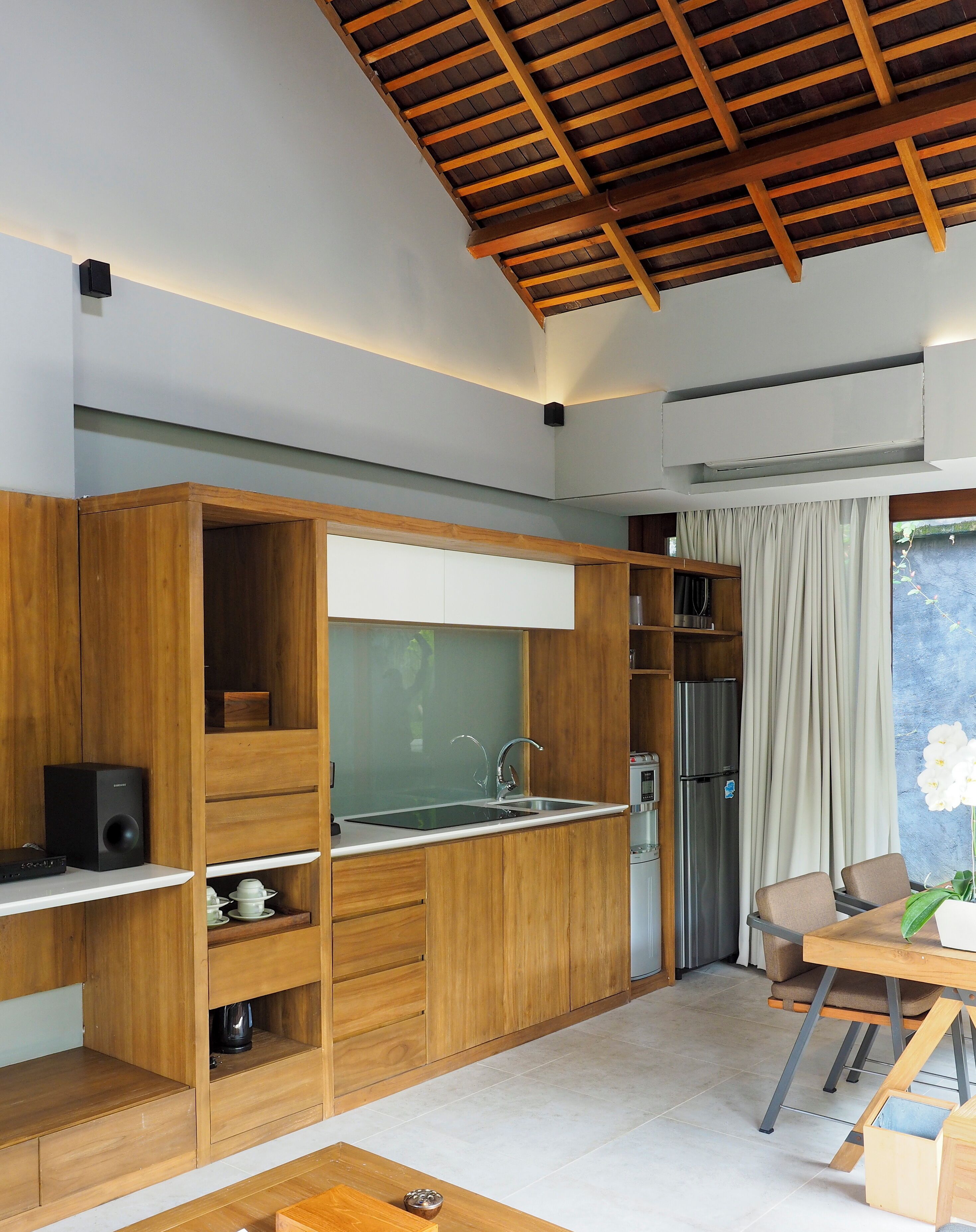 A modern kitchen with wooden cabinetry, a built-in sink, and a dining area with a table and chairs.