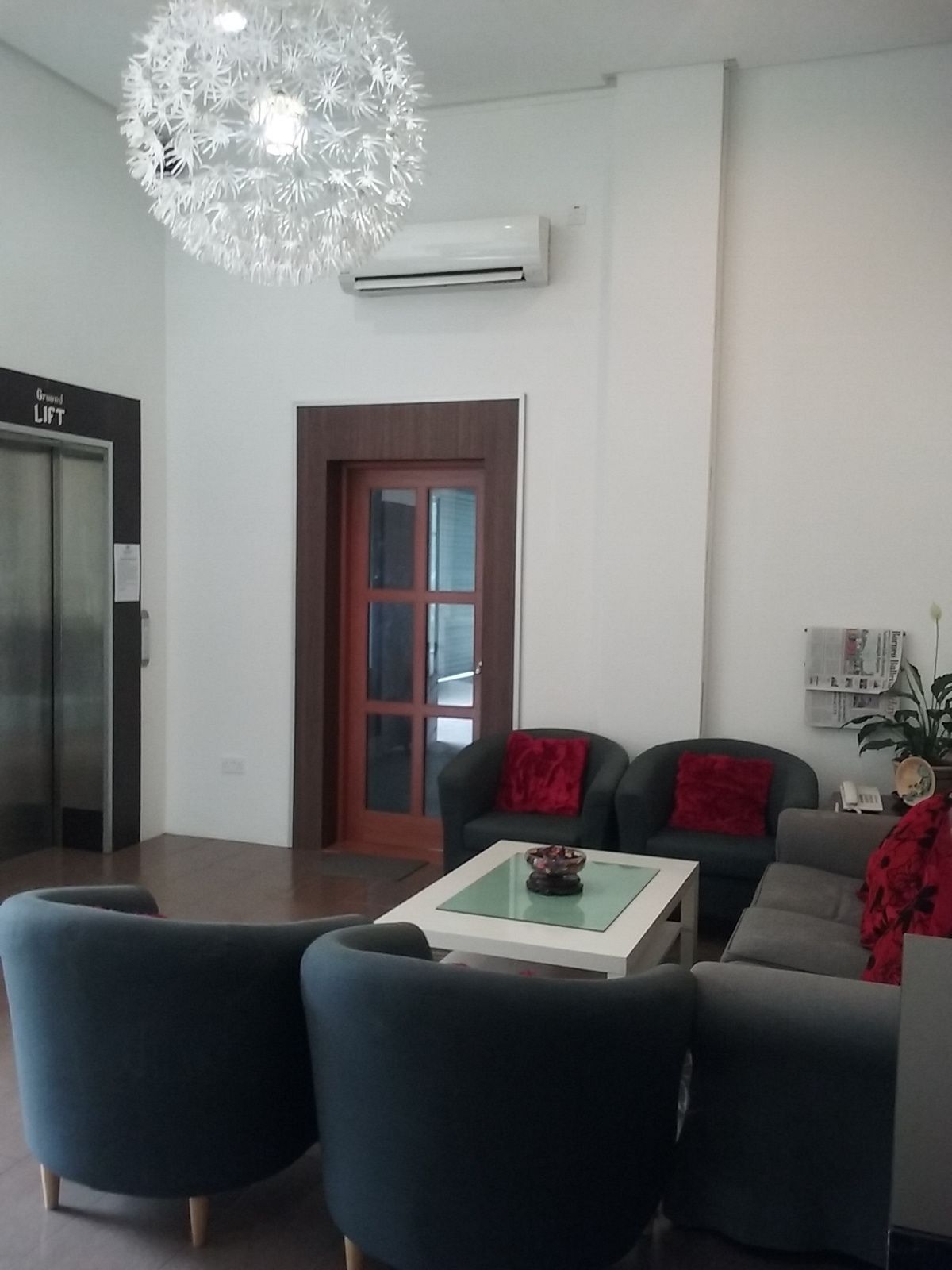 A modern living room with a glass coffee table, two sofas, and a decorative chandelier.