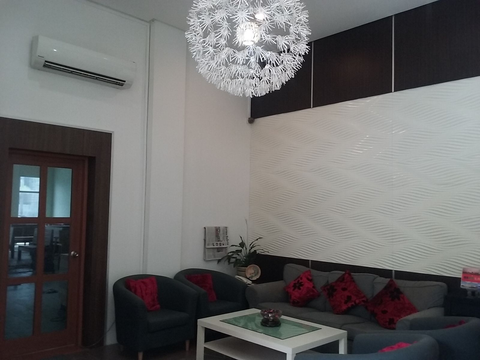 Un salon moderne comprenant un canapé, des fauteuils, une table basse et un luminaire décoratif au plafond.
