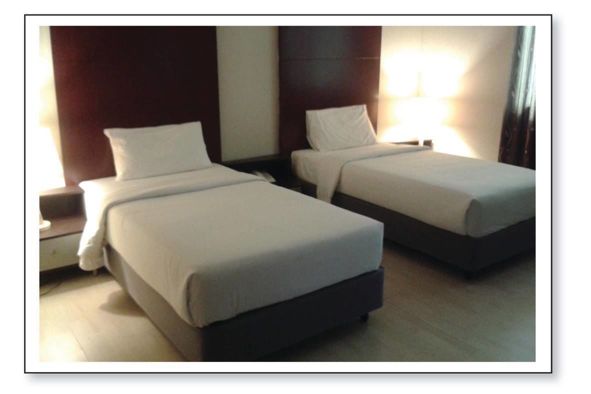 Two single beds with white linens in a hotel room.