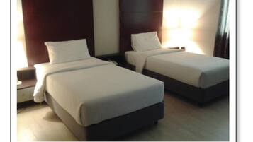 Two single beds with white linens in a hotel room.