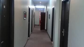 Un pasillo largo y estrecho con puertas a ambos lados, piso alfombrado e iluminación en el techo.
