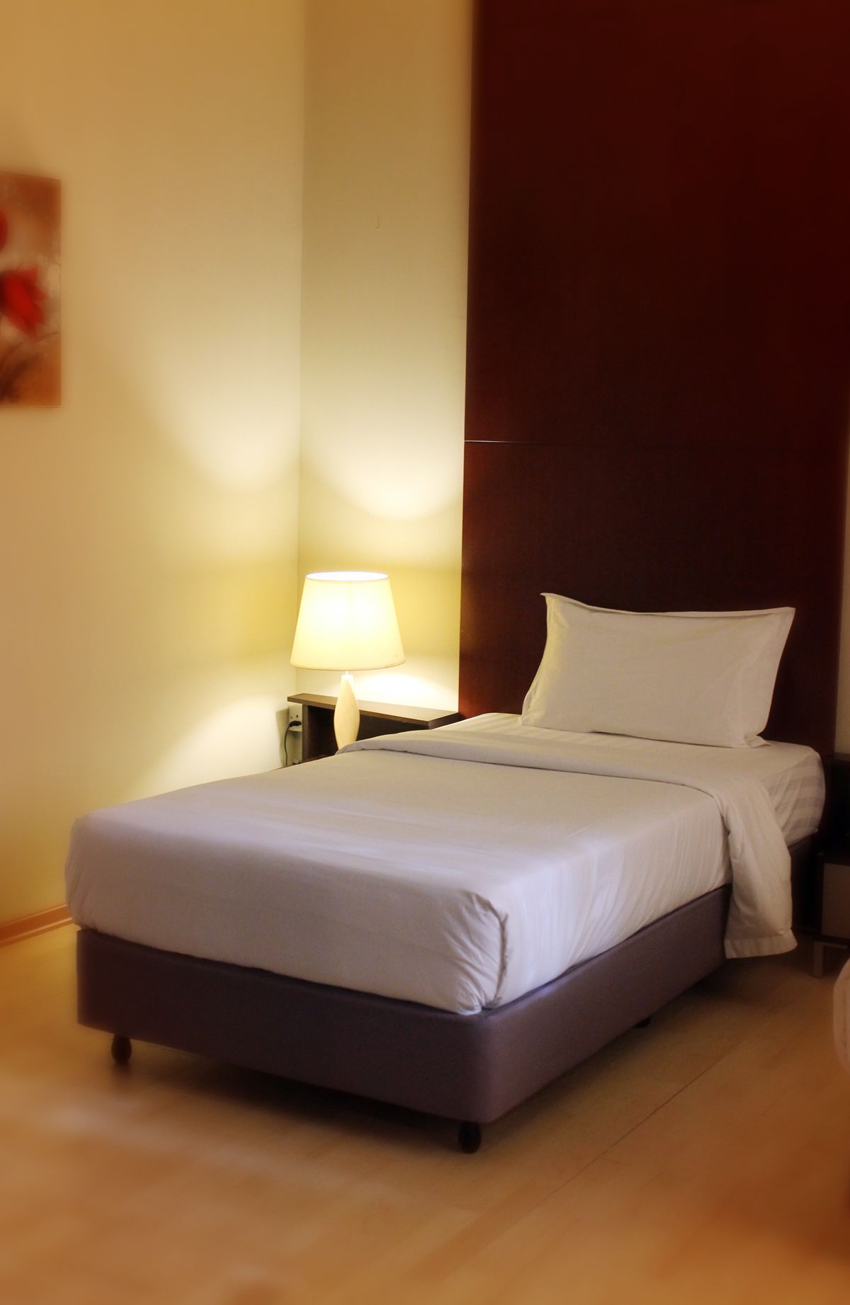 A neatly made bed with white linens in a hotel room.