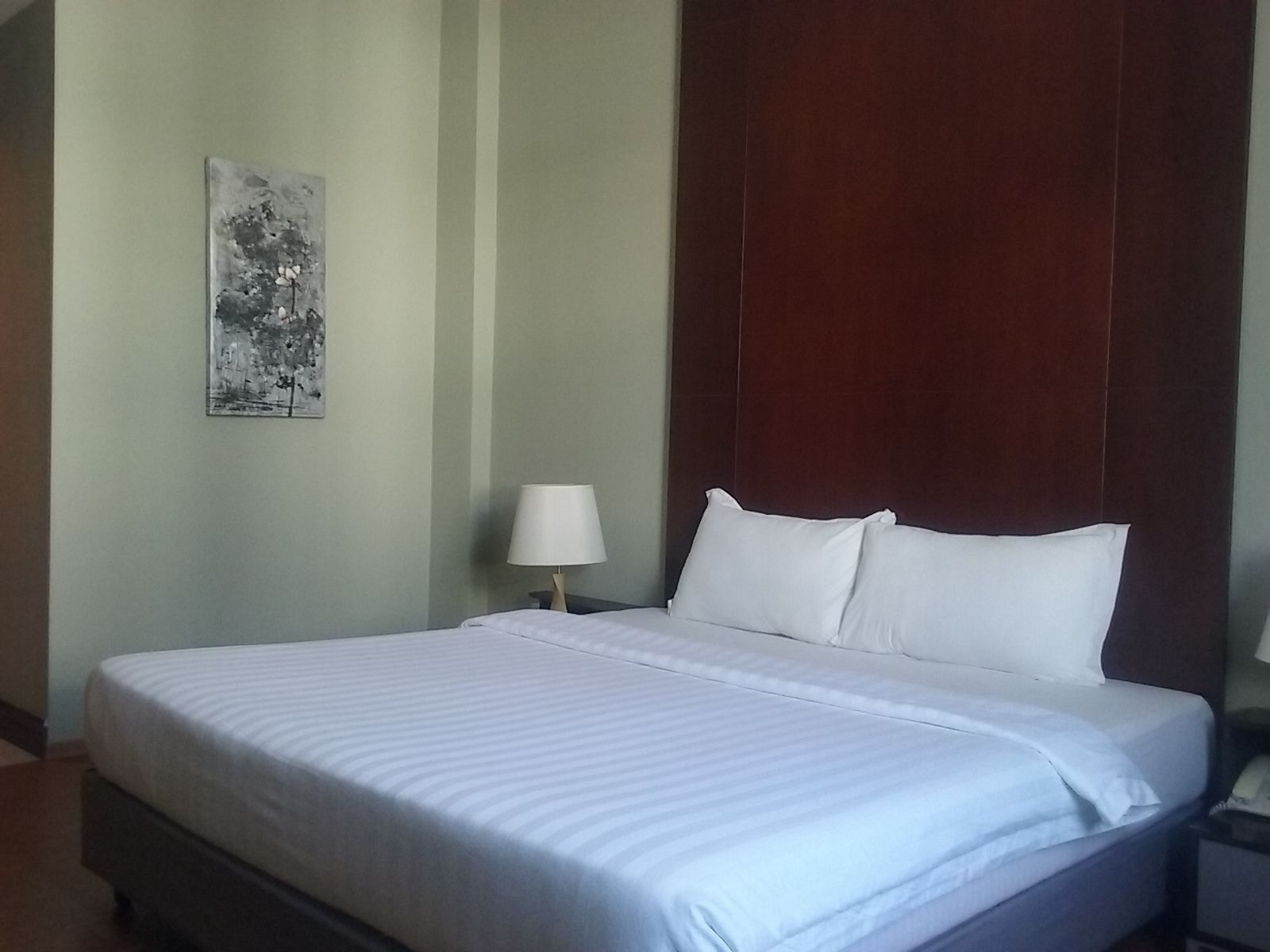 Una cama bien tendida con sábanas blancas en una habitación de hotel.
