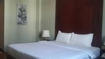 Una cama bien tendida con sábanas blancas en una habitación de hotel.