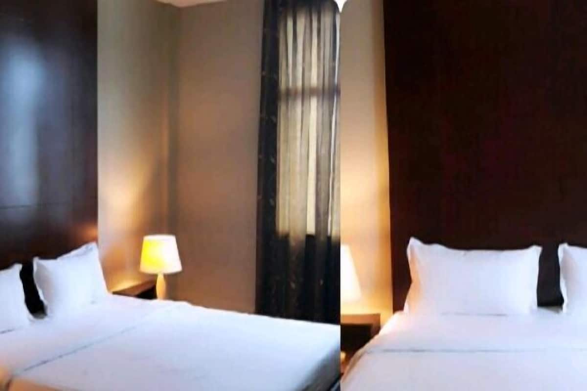 Een hotelkamer met een groot bed, twee nachtkastjes en een raam met gordijnen.
