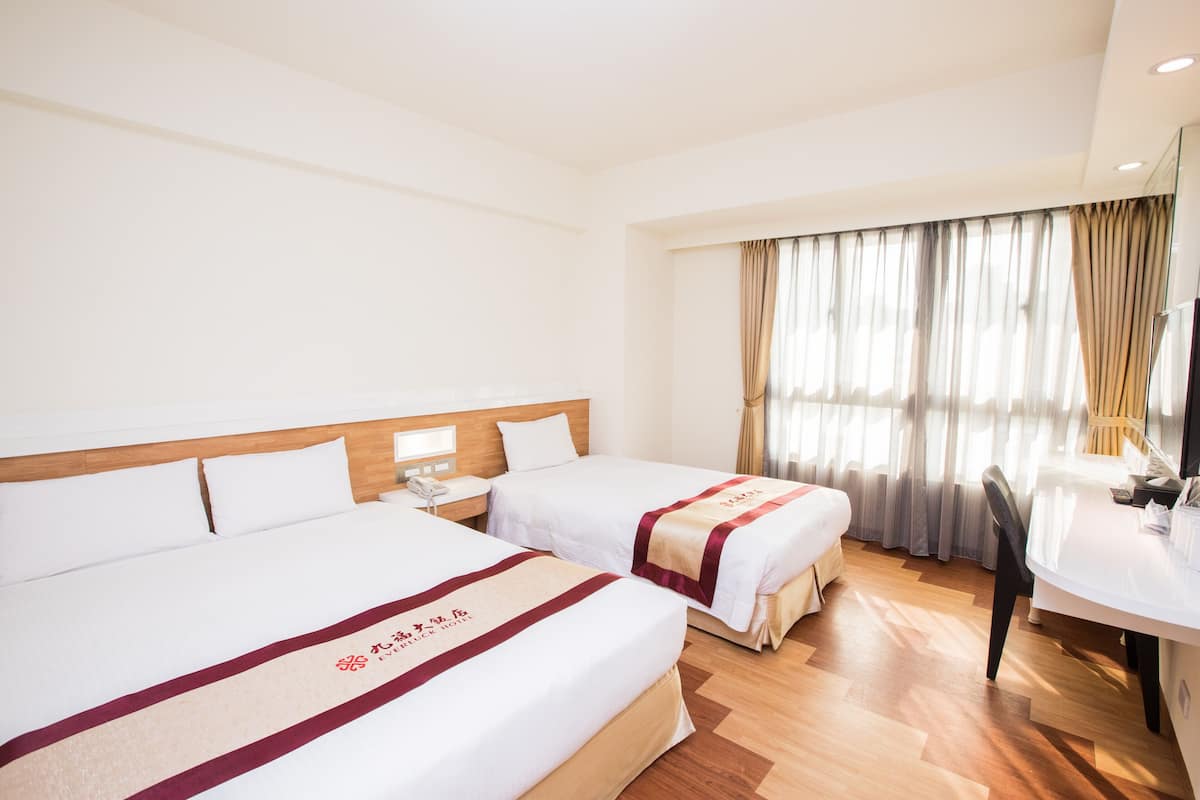 Hotellihuone, jossa on kaksi sänkyä, työpöytä ja tuoli.