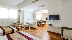 Une chambre d’hôtel avec deux lits, un bureau, une chaise, une télévision et une vue sur l’espace de vie.