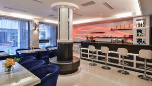 A modern bar area with a central column, seating, and a bar counter with shelves of bottles. - Harmonious Hotel (Kaohsiung)
