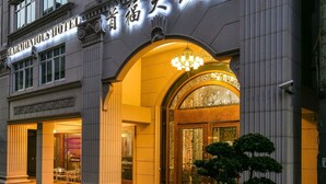 A hotel with a grand entrance, multiple floors, and flags on the roof. - Harmonious Hotel (Kaohsiung)